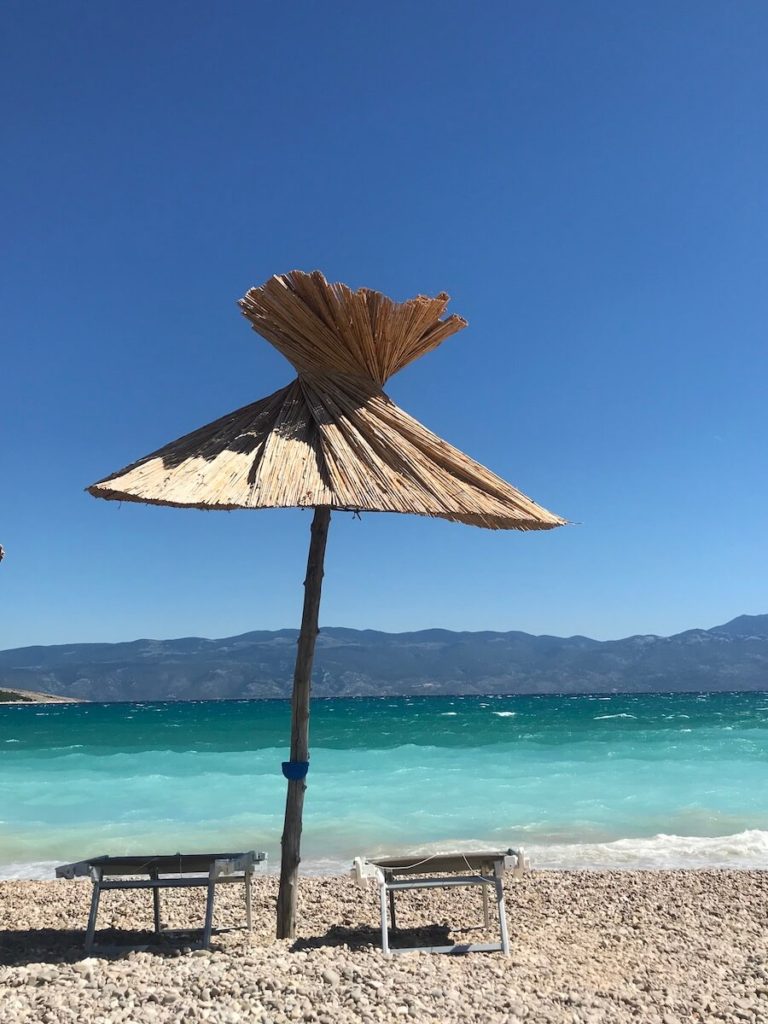 Baska beach or Vela plaža with turquoise sea and two sunbeds with a sun umbrella